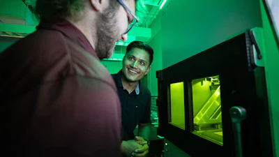 Mechanical engineering master’s students Reese Rodely (left) and Kamal Kunwar discuss what they are observing in SIU Carbondale’s 3D metal printer.