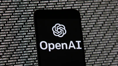 The OpenAI logo appears on a mobile phone in front of a computer screen with random binary data, March 9, 2023, in Boston.