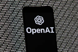 The OpenAI logo appears on a mobile phone in front of a computer screen with random binary data, March 9, 2023, in Boston.