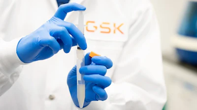 Scientist holding lab syringe in a GSK facility.