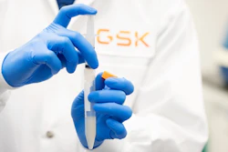 Scientist holding lab syringe in a GSK facility.