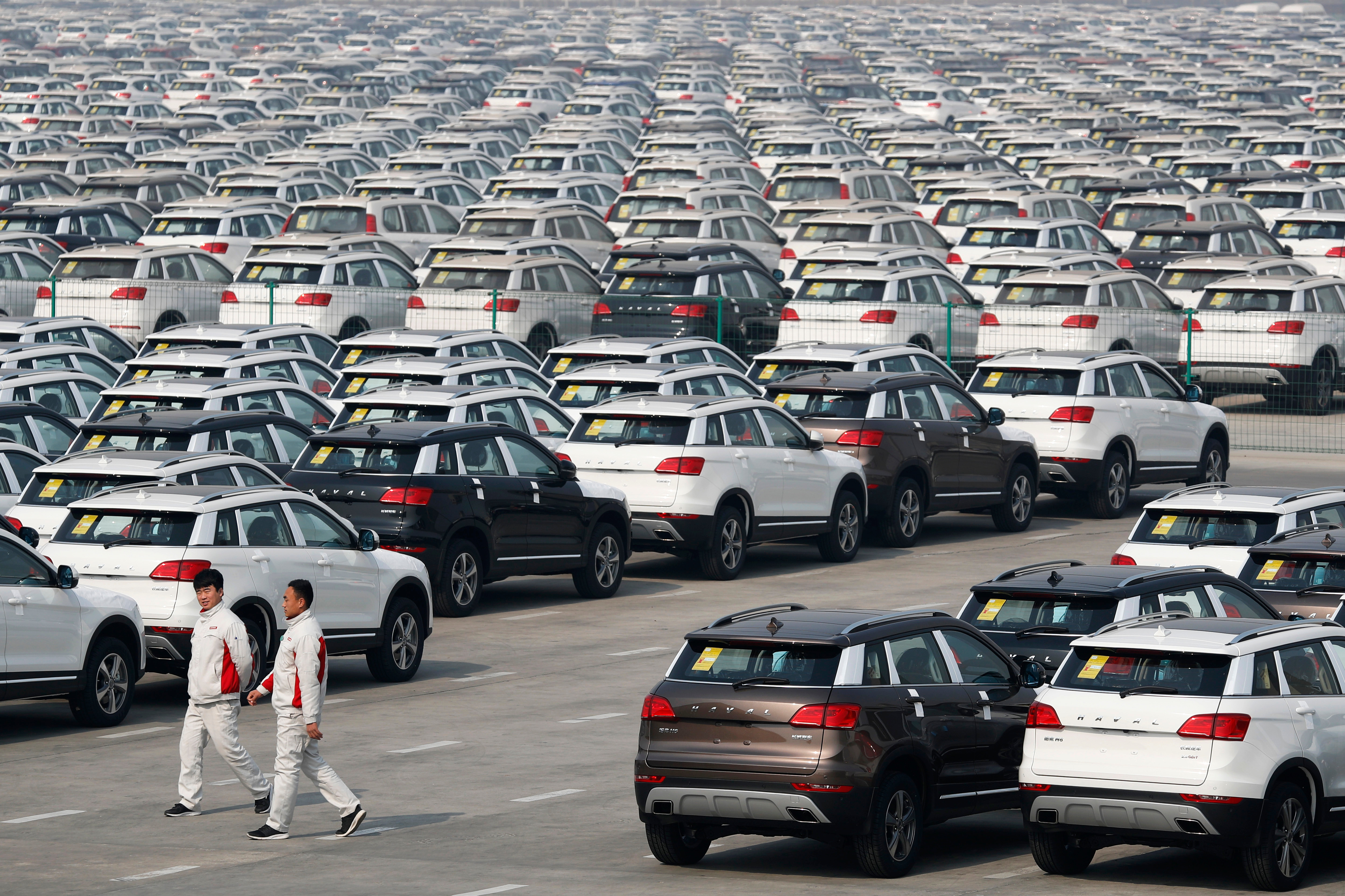 Workers walk past Haval SUV models parked outside the Great Wall Motors assembly plant in Baoding in north China's Hebei province.