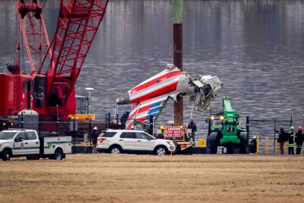 A crane offloads a piece of wreckage from a salvage vessel onto a flatbed truck, near the wreckage site in the Potomac River of a mid-air collision between an American Airlines jet and a Black Hawk helicopter, at Ronald Reagan Washington National Airport, Feb. 5, 2025, in Arlington, Va.