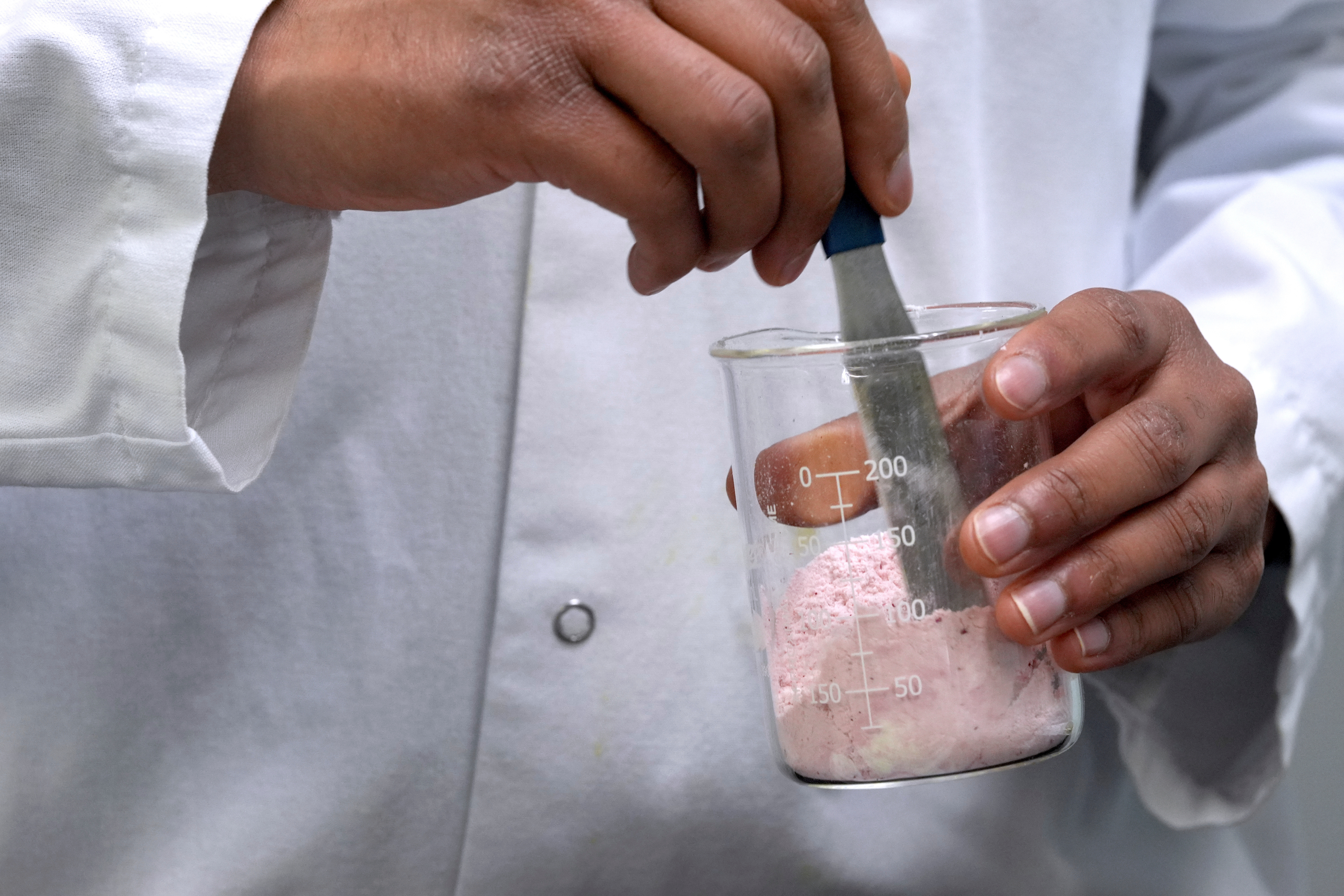 Applications Scientist Anuj Bag mixes coloring with flour at Sensient Technologies Corp., a color additive manufacturing company, April 2, 2025, in St. Louis.