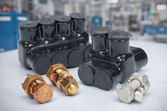 Industrial electrical connectors and copper terminal lugs displayed on white surface with factory background