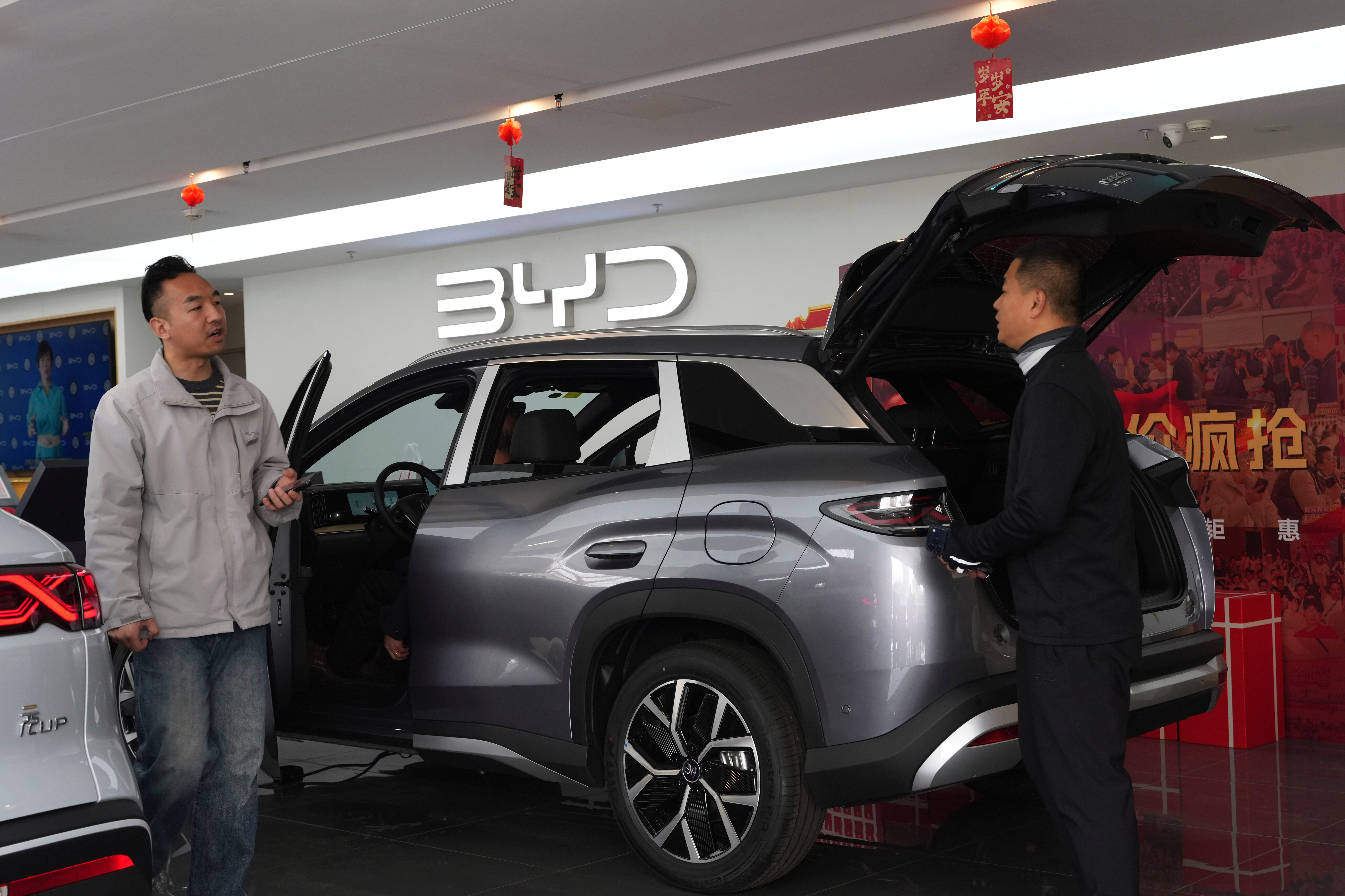Visitors walk by a hybrid car at a BYD showroom in Beijing, China, Thursday, March 26, 2026.