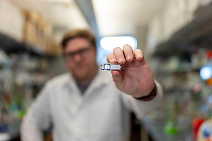 Rice University Ph.D. student Chris Wright holds the implant, which uses cells to manufacture pharmaceutical drugs beneath the skin.
