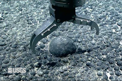 A metal claw reaches for an iron and manganese nodule on the seabed for testing.