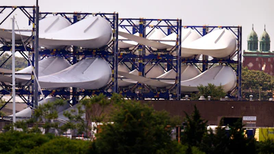 Giant wind turbine blades for the Vineyard Winds project are stacked on racks in the harbor, July 11, 2023, in New Bedford, Mass.
