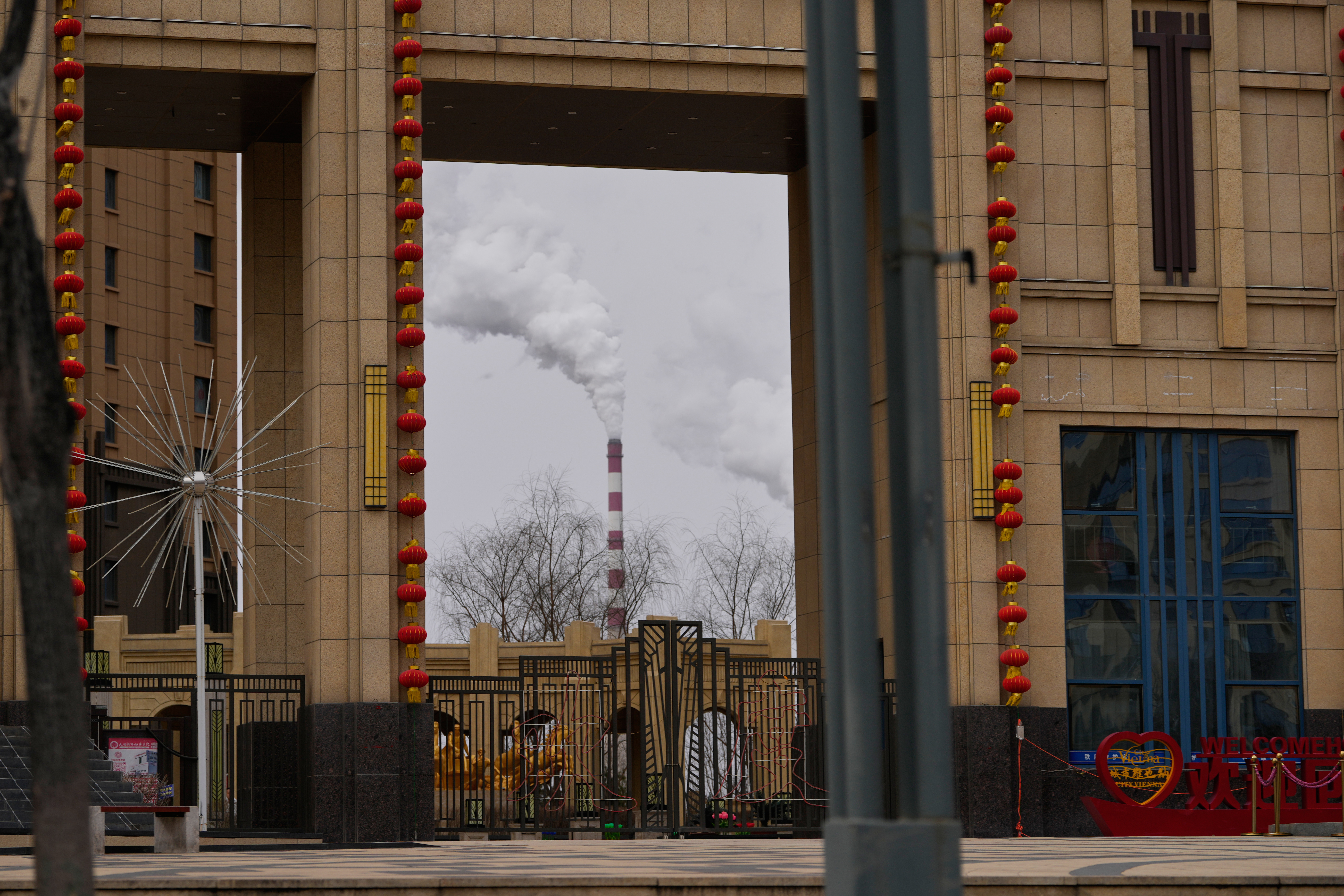 A chimney of a coal-fired power plant is visible near a residential complex in Datong, China, March 14, 2026.