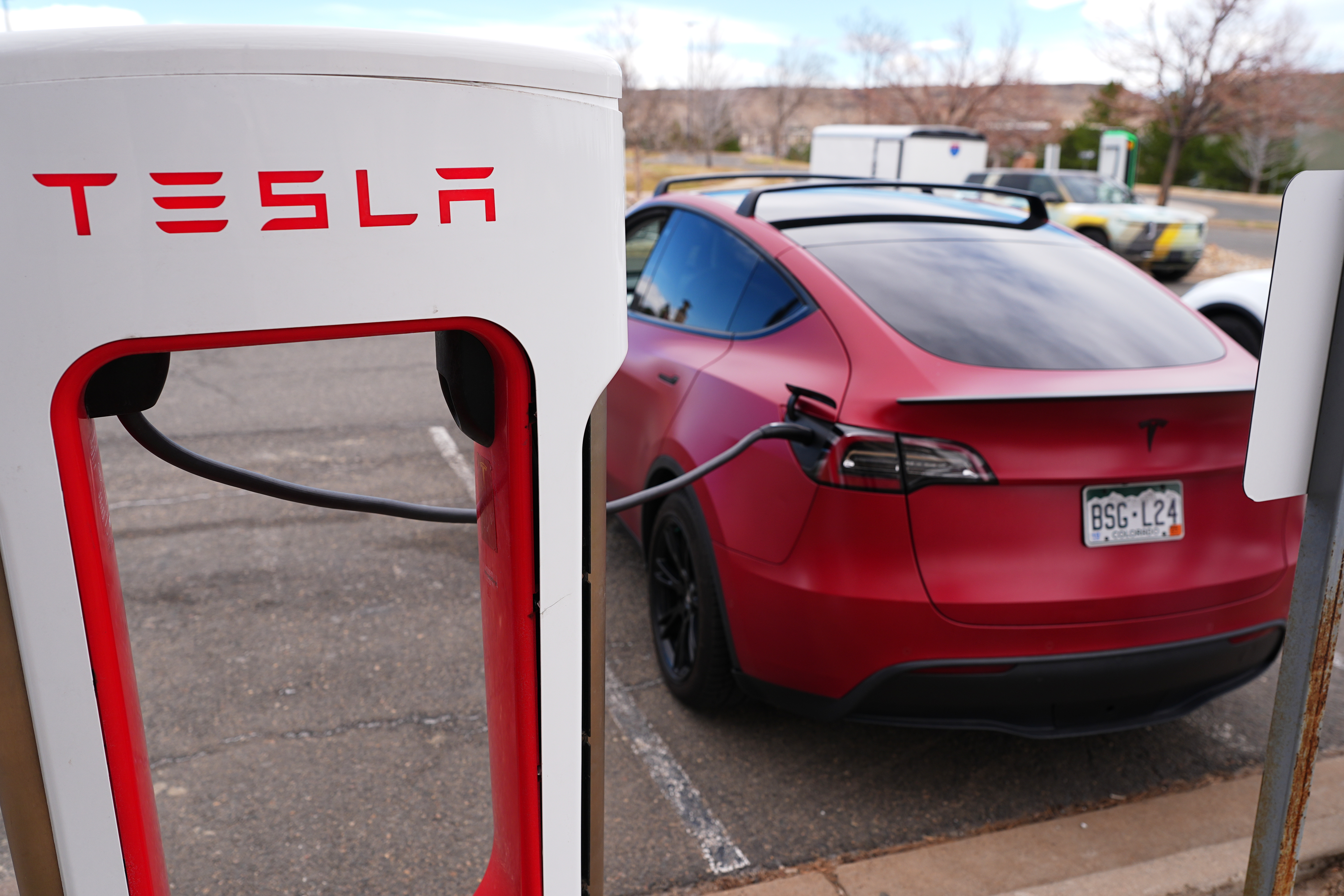 A motorist sits in a Tesla Model 3 at a Tesla charging station Friday, March 13, 2026, in Lakewood, Colo., in Denver.