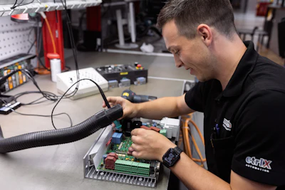 Technician working on circuit board assembly with soldering equipment in electronics repair workshop