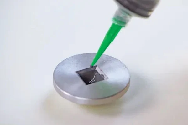 Green-handled applicator tool demonstrating application on circular metallic surface