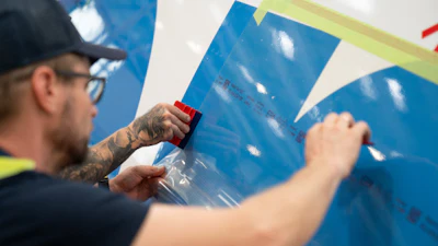 Worker applying protective film to blue surface during installation or renovation project