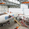 Flydubai aircraft undergoing maintenance in industrial hangar with orange support equipment and scaffolding