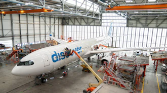 Flydubai aircraft undergoing maintenance in industrial hangar with orange support equipment and scaffolding