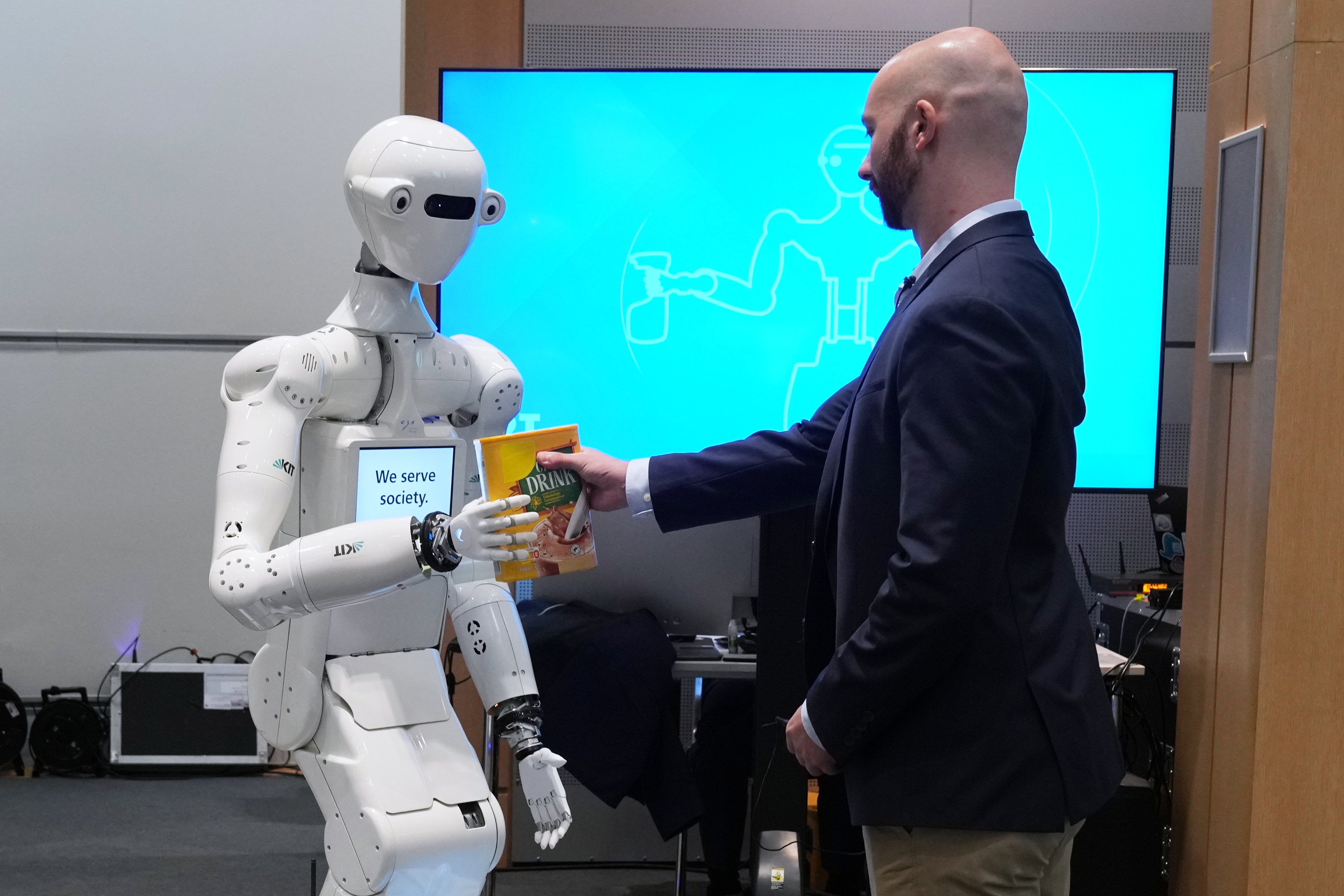 A man receives a box of chocolate powder drink from a robot during a demonstration of AI-based robotics in Europe at the European Parliament in Brussels, Wednesday, Sept. 2, 2026.