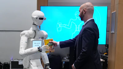 A man receives a box of chocolate powder drink from a robot during a demonstration of AI-based robotics in Europe at the European Parliament in Brussels, Wednesday, Sept. 2, 2026.