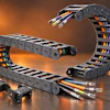 Industrial cable management system with multi-colored wires in flexible drag chain housings against warm orange background