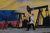 A pedestrian walks past a mural featuring oil wells in Caracas, Venezuela, Saturday, Aug 29, 2026, a day after President Donald Trump announced a deal giving the United States a stake in Venezuela’s oil reserves.