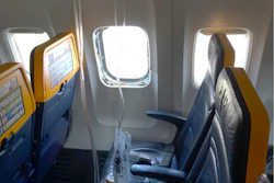 This undated photo provided by the National Transportation Safety Board on Thursday, Aug. 13, 2026, shows the shattered window on a Ryanair plane that was broken by a stray engine part shortly after takeoff, causing a man's head to be sucked into the hole.
