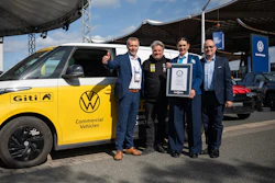 Five men pose with yellow Volkswagen Giti electric commercial vehicle and Guinness World Record certificate at outdoor event