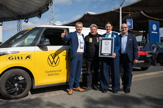 Five men pose with yellow Volkswagen Giti electric commercial vehicle and Guinness World Record certificate at outdoor event