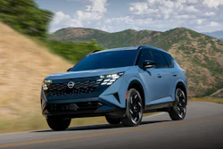 Light blue Nissan Ariya electric SUV driving on a mountain road with scenic hills in the background