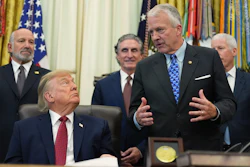 Formal meeting in the Oval Office with government officials and American flags in background