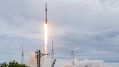 Rocket launching vertically with bright engine flames against cloudy sky and launch pad infrastructure visible below