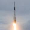Rocket launching vertically with bright orange flame exhaust against cloudy sky