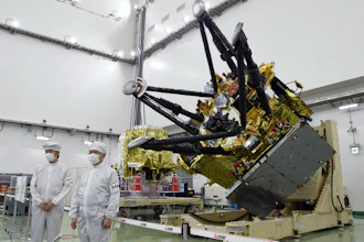 Satellite component with gold thermal insulation and black mechanical arms in clean room facility with technicians in protective suits