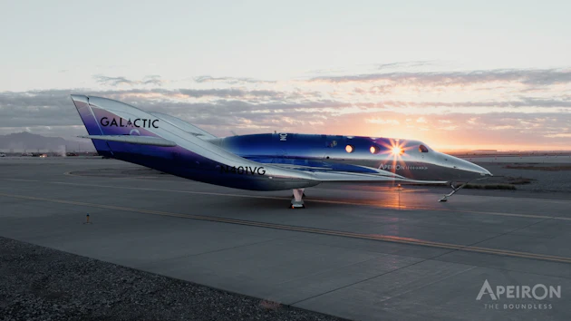 Virgin Galactic SpaceShipTwo aircraft on runway at sunset with illuminated cabin windows