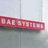 BAE Systems red and white exterior building sign mounted on modern facade with natural sunlight