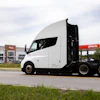 White semi-truck parked at Plas fuel station with open sleeper cab door