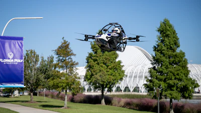Police drone in flight over Florida Poly campus with trees and modern architecture in background