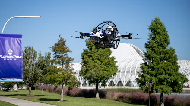 Police drone in flight over Florida Poly campus with trees and modern architecture in background