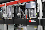 Bright Machines industrial robotic assembly system with red frame, articulated robot arm, and integrated control display