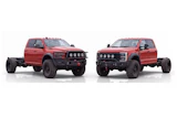 Two red lifted pickup trucks with custom front bumpers and roof lights displayed side by side