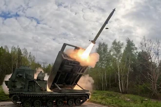Military MLRS launcher firing a long-range missile in a forest clearing with smoke and flames visible