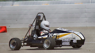 Black and white formula SAE race car with number 35 on concrete track near barrier