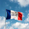 Iowa state flag waving on a flagpole against a blue sky with white clouds