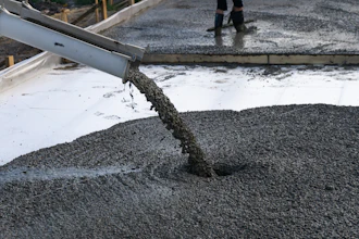 Concrete being poured from a chute during construction work on a wet surface