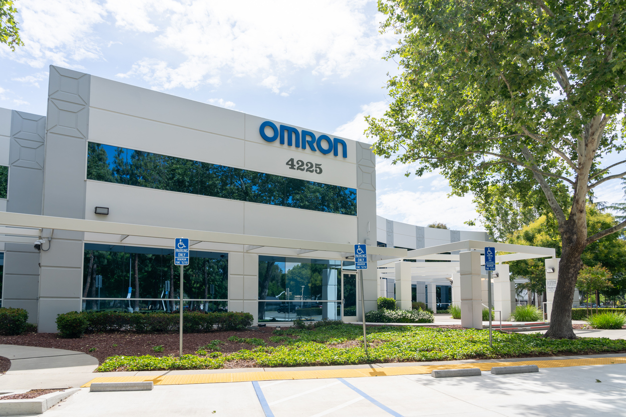 Omron corporate office building exterior with blue signage, address 4225, landscaping, and accessible parking spaces