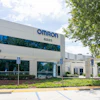 Omron corporate office building exterior with blue signage, address 4225, landscaping, and accessible parking spaces