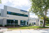 Omron corporate office building exterior with blue signage, address 4225, landscaping, and accessible parking spaces