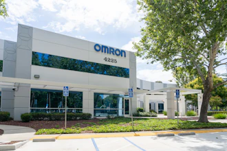 Omron corporate office building exterior with blue signage, address 4225, landscaping, and accessible parking spaces