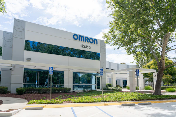 Omron corporate office building exterior with blue signage, address 4225, landscaping, and accessible parking spaces