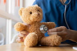 Healthcare professional using stethoscope to examine teddy bear during pediatric medical examination