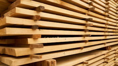 Stacked wooden planks with natural grain texture stored in a warehouse or lumber yard